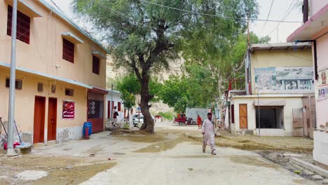 Toma-Frontal-De-Algunas-Personas-Y-Vacas-Caminando-Por-El-Camino-De-Mata-Mandir-En-Hingol,-Baluchistán-Con-Hermosas-Montañas-Al-Fondo-Durante-El-Día-En-Pakistán