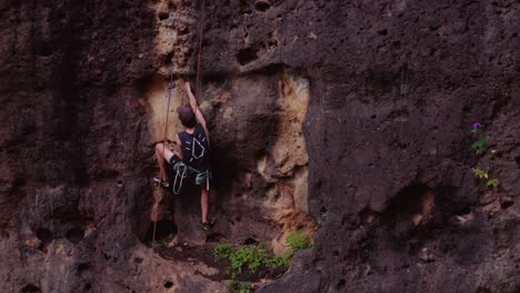 Climber-searching-for-hand-hold-while-climbing-cliff-face