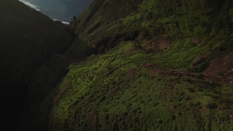 Toma-Aérea-De-Un-Dron-De-Una-Pintoresca-Vista-Costera-De-Un-Acantilado-Verde-Al-Atardecer-Con-Brillo-Oceánico-Y-Nubes-De-Lluvia