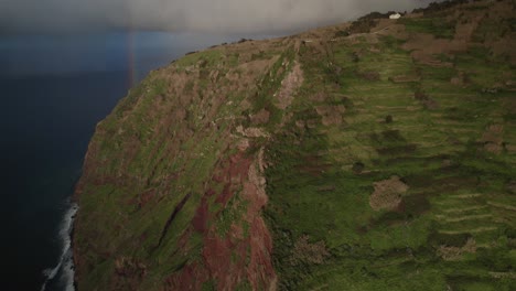 Vista-Aérea-Con-Drones-De-Acantilados-Escarpados-Junto-Al-Océano-Con-Un-Arco-Iris-Y-Olas-En-Madeira