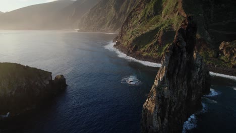 Aerial-view-with-drone-of-rugged-cliffs-and-isolated-rocks-in-the-ocean-during-golden-hour