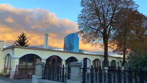 Bombed-and-destroyed-tall-skyscraper-building-with-broken-glass-windows-near-the-train-station-in-Kyiv-Ukraine,-critical-war-damage-in-the-city-capital,-nice-orange-clouds,-4K-shot