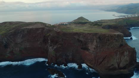 Drohne-Fliegt-über-Das-Meer-An-Der-Küste-Von-Ponta-Do-Rosto,-Madeira,-Während-Im-Hintergrund-Eine-Landschaft-Mit-Wellen-Und-Bergen-Auf-Madeira-Sichtbar-Ist