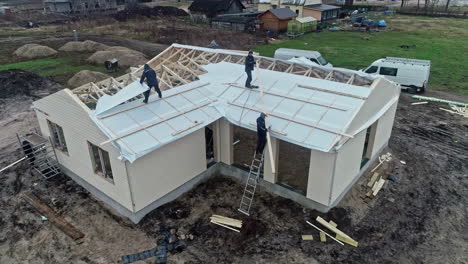 Vista-Aérea-De-Los-Trabajadores-En-El-Marco-De-Una-Casa-En-Un-Sitio-De-Construcción-Durante-El-Día.