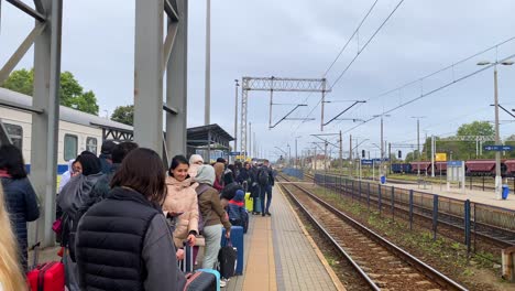 Ukrainian-refugees-waiting-for-a-train-to-arrive-at-the-Chelm-train-station-in-Poland,-people-fleeing-and-escaping-war,-cloudy-day,-4K-shot