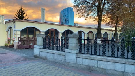 Bombed-and-destroyed-tall-skyscraper-building-with-broken-glass-windows-near-the-train-station-in-Kyiv-Ukraine,-critical-war-damage-in-the-city-capital,-orange-clouds,-4K-shot