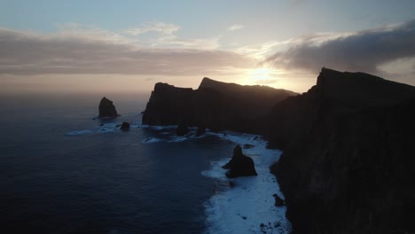 Drohne-Fliegt-Bei-Sonnenuntergang-über-Dem-Blauen-Ozean-An-Der-Zerklüfteten-Küste-Von-Madeira