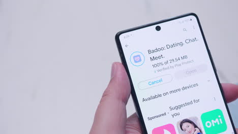 Primer-Plano-De-Un-Teléfono-Móvil-Inteligente-Mientras-Un-Individuo-Descarga-E-Instala-La-Aplicación-De-Citas-Badoo