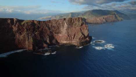 Drone-Volando-Sobre-El-Océano-Y-Ve-Una-Vista-Panorámica-De-Imponentes-Acantilados-Contra-Un-Océano-En-Calma