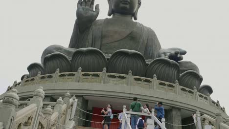 Tian-Tan-Buddha-Statue-An-Einem-Bewölkten-Tag-Mit-Vielen-Touristen-Unten,-Die-Fotos-Machen-Und-Sehenswürdigkeiten-Besichtigen-–-Superzeitlupe