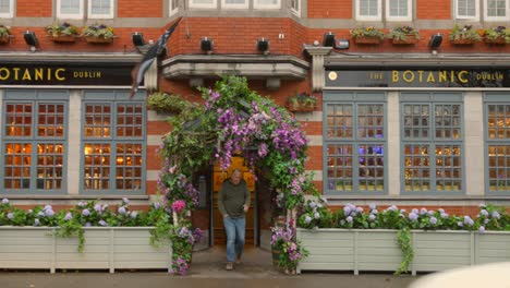 Zwei-Männer-Verlassen-Das-Berühmte-Dubliner-Botanic-Pub-Mit-Blumengirlandentür