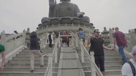 Tian-Tan-Buddha-statue-during-an-overcast-day-with-many-tourists-below-taking-pictures-and-sightseeing---Super-Slow-Motion