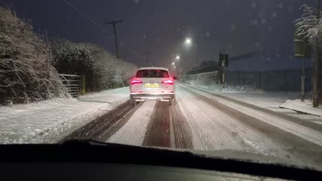 Windshield-POV-carefully-driving-in-snowy-slow-traffic-at-night