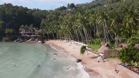 Vuelo-Aéreo-A-Lo-Largo-De-La-Playa-Sairee-Bordeada-De-Palmeras-Tropicales-Y-Olas-Rompiendo