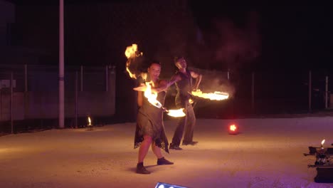 Feuriges-Duo:-Feuerspucker-Und-Feuerspucker-Drehen-Den-Flammenstab-In-Hypnotisierender-Darbietung