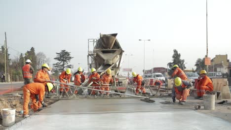 Trabajadores-De-La-Construcción-Con-Ropa-De-Alta-Visibilidad-Nivelando-Hormigón-Fresco-En-La-Carretera