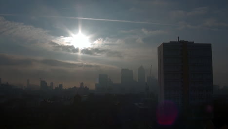 Wolken-Ziehen-Langsam-Vorbei,-Am-Frühen-Morgen-Geht-Die-Sonne-über-Eiskaltem-Nebel-Auf,-Der-Das-Finanzviertel-Canary-Wharf-Und-Die-East-End-Estates-Bedeckt