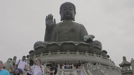 Tian-Tan-Buddha-Statue-An-Einem-Bewölkten-Tag-Mit-Vielen-Touristen-Unten,-Die-Fotos-Machen-Und-Sehenswürdigkeiten-Besichtigen-–-Superzeitlupe