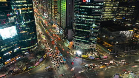 Tráfico-Nocturno-En-La-Calle-Principal-De-Gangnam-Y-Rascacielos-De-Oficinas-En-Seúl---Hiperlapso-Aéreo,-Autos-Cruzando-Cruces-Atascados---Alejar-El-Zoom