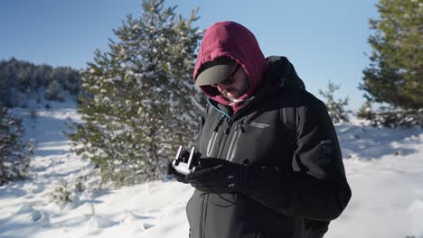 Junger-Männlicher-Drohnenpilot,-Der-Seine-Drohne-Fliegt,-Schneebedeckter-Bergwald-Im-Winter