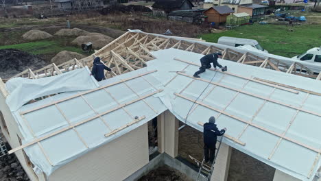 Trabajadores-Instalando-El-Techo-De-Una-Casa-Nueva-En-El-Sitio-De-Construcción-Al-Atardecer