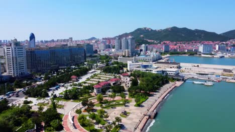 Vista-Aérea-Panorámica-En-Bucle-De-360-Grados-Del-Hermoso-Paisaje-Urbano-De-La-Ciudad-De-Weihai-En-El-Parque-Xingfu-Junto-Al-Mar-Con-La-Isla-Al-Fondo