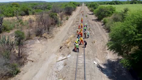 Trabajadores-Con-Ropa-De-Alta-Visibilidad-Colocando-Vías-De-Ferrocarril-En-Un-Entorno-Rural,-En-La-Provincia-De-Salta.