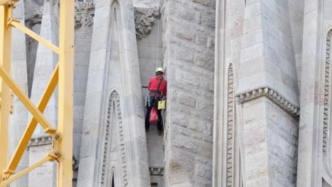 Trabajador-Masculino-En-La-Fachada-De-La-Sagrada-Familia-Mejorando-La-Fachada-De-La-Iglesia-En-Barcelona,-Plano-Medio