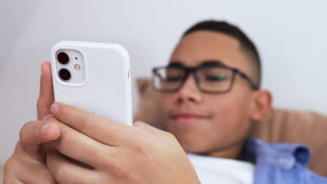 Young-boy-using-phone-on-bed