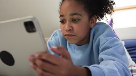 Young-girl-using-tablet-on-bed