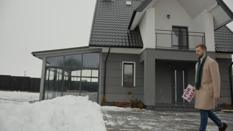 Immobilienmakler-Setzt-Schild-Auf-Den-Schnee