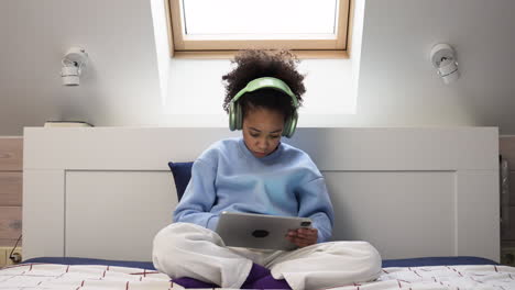 Young-girl-using-headphones-on-bed