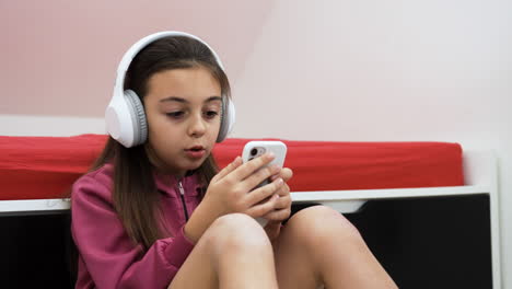 Niña-Usando-Auriculares-Y-Teléfono-Inteligente