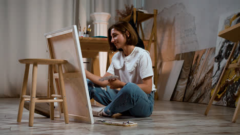 Young-woman-sitting-on-the-floor-with-canvas