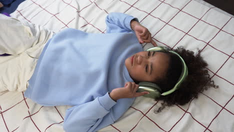 Young-girl-using-headphones-on-bed