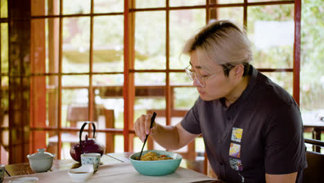 Asian-woman-eating-ramen-while-he-is-sitting-at-a-table-in-a-japanese-home