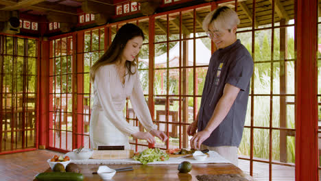 Asian-couple-talking-about-the-fresh-fish-to-make-sushi-near-a-table-at-home