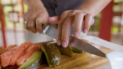 Close-up-view-of-asian-man-hands-cutting-avocado-on-top-of-a-kitchen-board-at-home