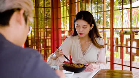 Asiatisches-Paar-Isst-Ramen-Und-Unterhält-Sich,-Während-Sie-Mit-Tassen-Tee-An-Einem-Tisch-In-Einem-Japanischen-Haus-Sitzen