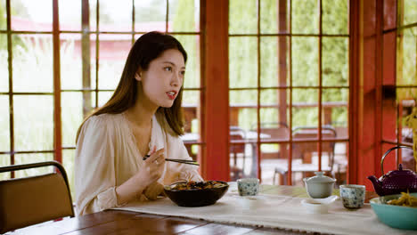 Asian-couple-eating-ramen-and-talking-while-they-are-sitting-at-a-table-with-cups-of-tea-in-a-japanese-home