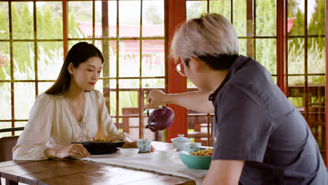 Pareja-Asiática-Comiendo-Ramen-Y-Bebiendo-Té-Mientras-Están-Sentados-En-Una-Mesa-En-Una-Casa-Japonesa