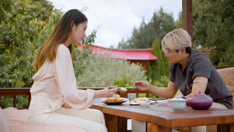 Asian-couple-eating-sushi-while-they-are-talking-sitting-on-a-japanese-garden-porch