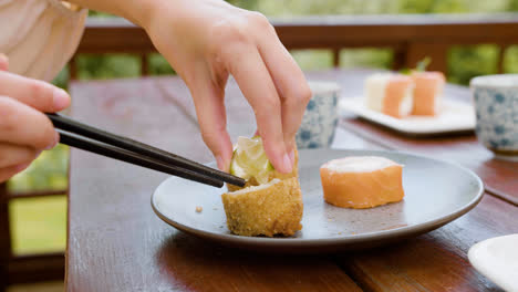 Close-up-view-of-hands-of-a-woman-garnishing-sushi-with-lemon-on-a-table-outdoors