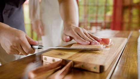 Close-up-view-of-hands-of-a-chef-cutting-fresh-fish-on-top-of-a-kitchen-board