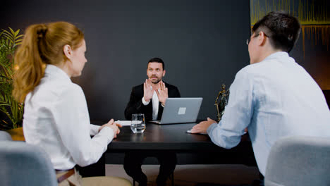 Caucasian-legal-advisor-sitting-at-a-table-with-laptop-in-the-office.-He-is-advising-a-couple