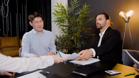 Close-up-view-of-group-of-multiethnic-legal-advisors-talking-and-reading-documents-sitting-at-a-table-in-the-office