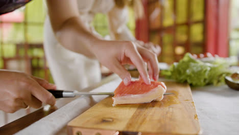 Close-up-view-of-hands-of-a-man-cutting-fresh-fish-on-top-of-a-kitchen-board