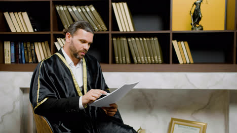 Camera-zoom-out-on-caucasian-male-legal-advisor-wearing-toga-and-sitting-on-a-chair-in-the-office.-He-is-advising-a-client