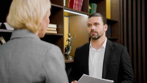 Close-up-view-of-caucasian-male-and-female-legal-advisors-talking-while-standing-in-the-office