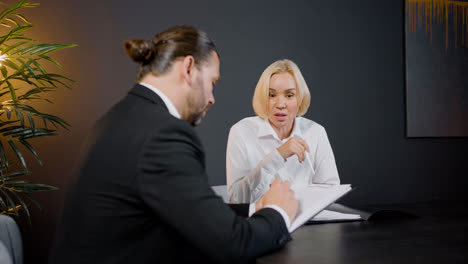 Close-up-view-of-caucasian-legal-advisors-talking-and-reading-documents-sitting-at-a-table-in-the-office